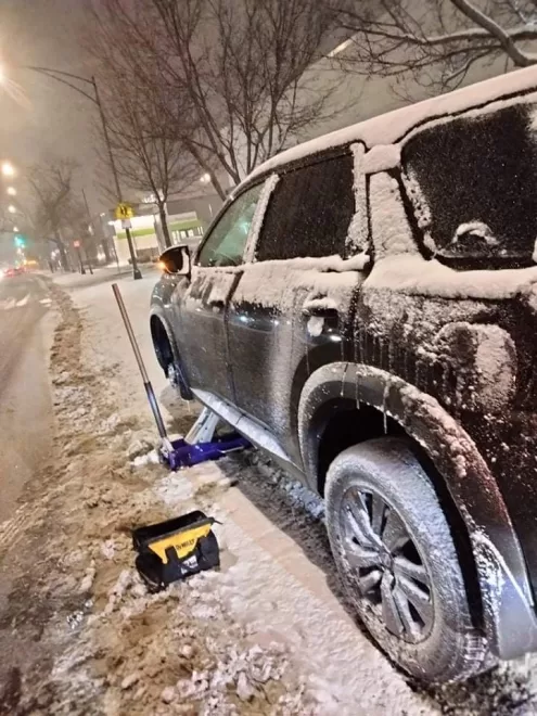 Emergency flat tire service in a Chicago winter snowstorm, with tools ready and snow-covered truck, demonstrating our reliable roadside assistance in extreme weather.