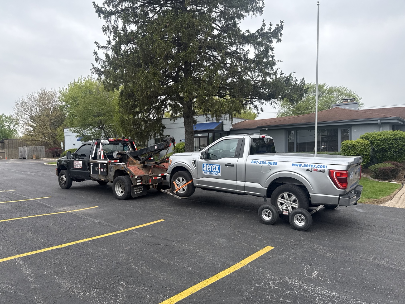 Commercial Ford F-150 work truck transported by wheel-lift tow truck and dollies to Rolling Meadows Illinois