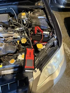 Red portable jump starter connected to a vehicle battery