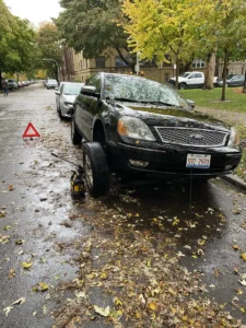 Black sedan floor jack on wet street.