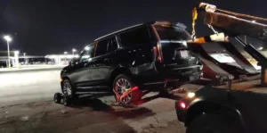 Black suv with wheel lift at night.