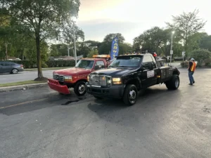 Black tow truck beside red pickup.