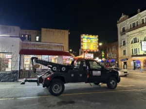 Black tow truck outside diner at night.