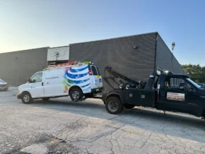 Black tow truck with branded white work van.