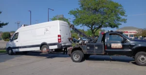 Black tow truck with white cargo van.