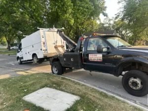 Black wheel lift truck with white utility vehicle.