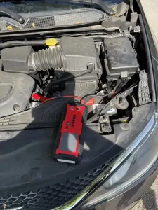 Portable jump starter connected in a car’s engine compartment