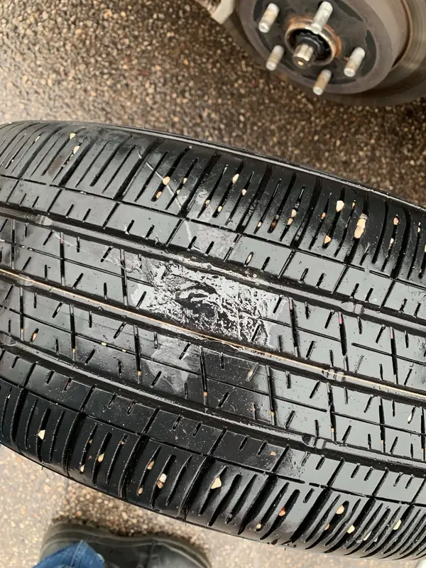Close view of damaged tire tread after the wheel was removed; tire safety requires professional assessment.