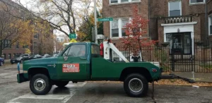 Green tow truck at residential intersection.