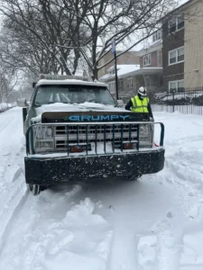 Green tow truck front view in snow.