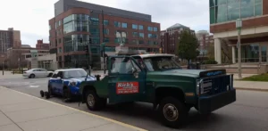 Green tow truck with blue compact car.