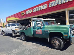 Green tow truck with silver suv at service shop.