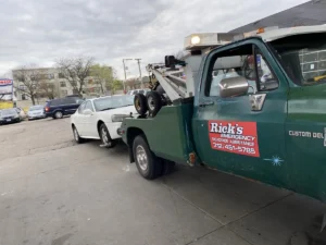 Green tow truck with white sedan.