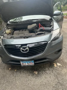 Mazda with hood open and battery clamp.