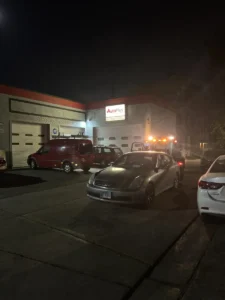 Nighttime sedan tow at repair shop.