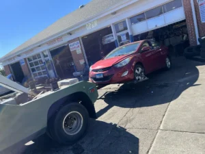 Red hatchback wheel lift at repair shop.