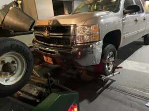 Silver chevrolet pickup wheel lift in garage.