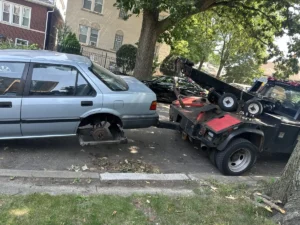 Silver sedan rear wheel lift at curb.
