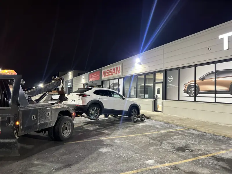 White SUV positioned on towing dollies behind Rick’s wheel-lift truck.